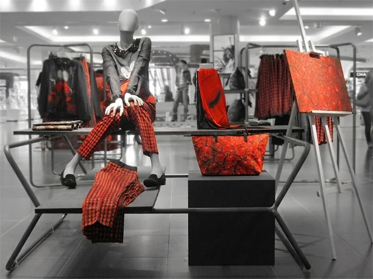 Warenpräsentation auf einer Aktionsfläche: Figur in rot-schwarz Kleidung sitzt auf einem Tischgestell, umgeben von passenden Accessoires